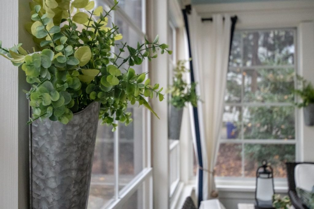 Bright sunroom with white curtains, wall-mounted greenery, and large windows letting in soft natural light