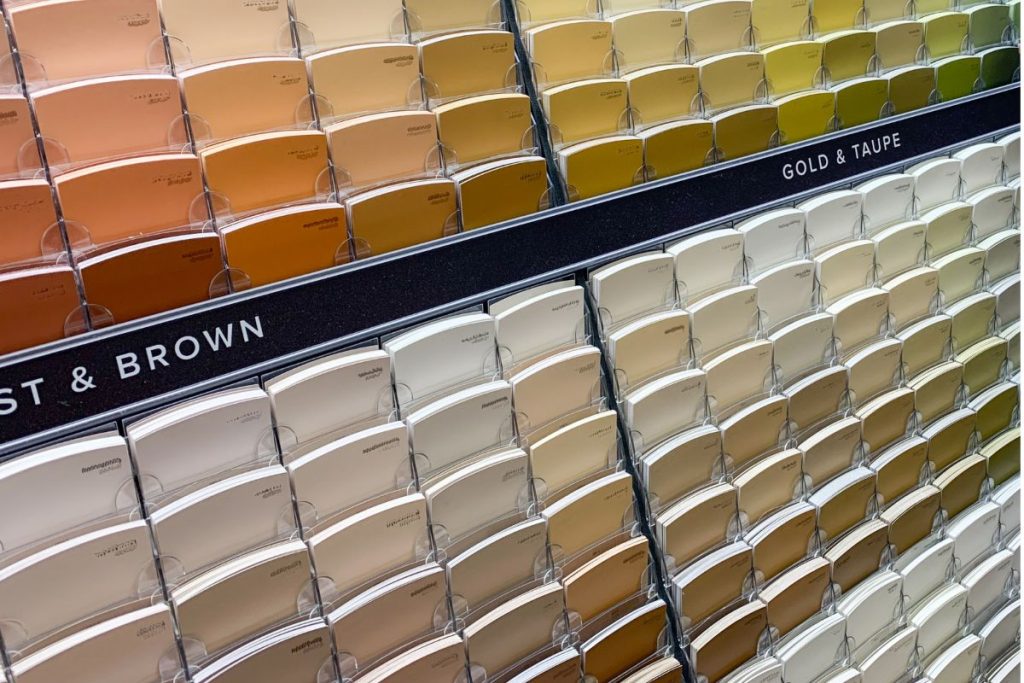 Wall display of gold, taupe, and brown paint swatches organized by shade in a home design store
